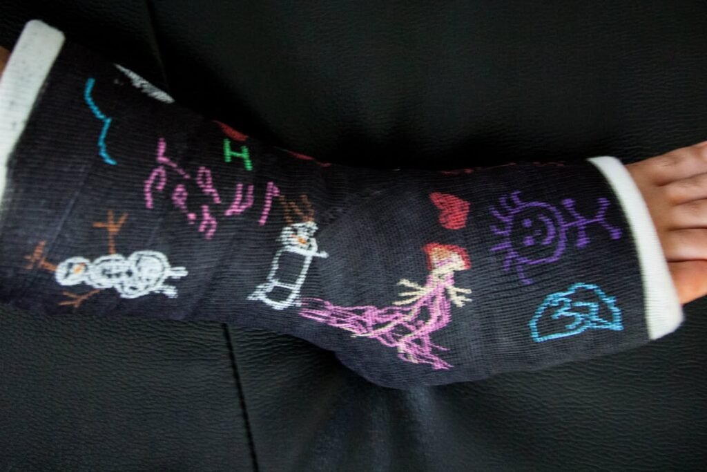 A black sock with colorful hand embroidery featuring stick figures, a sun, and the word 'Papa'.