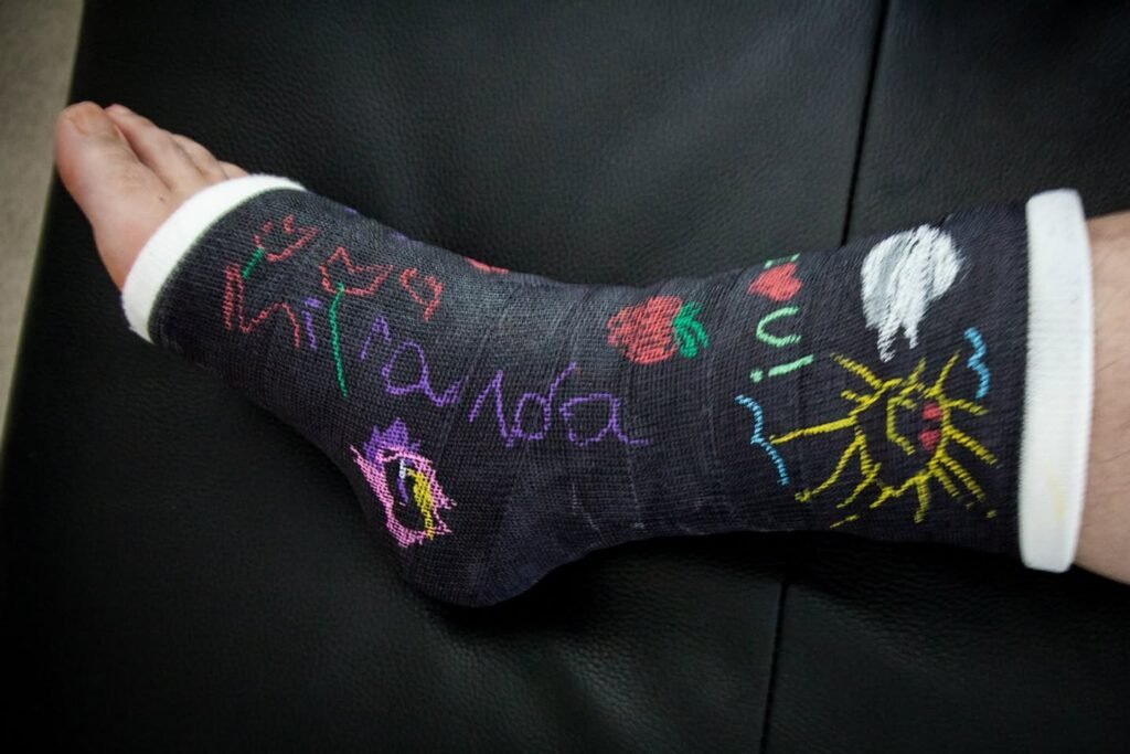 A close-up view of black socks featuring colorful drawings and writing created with fabric markers.