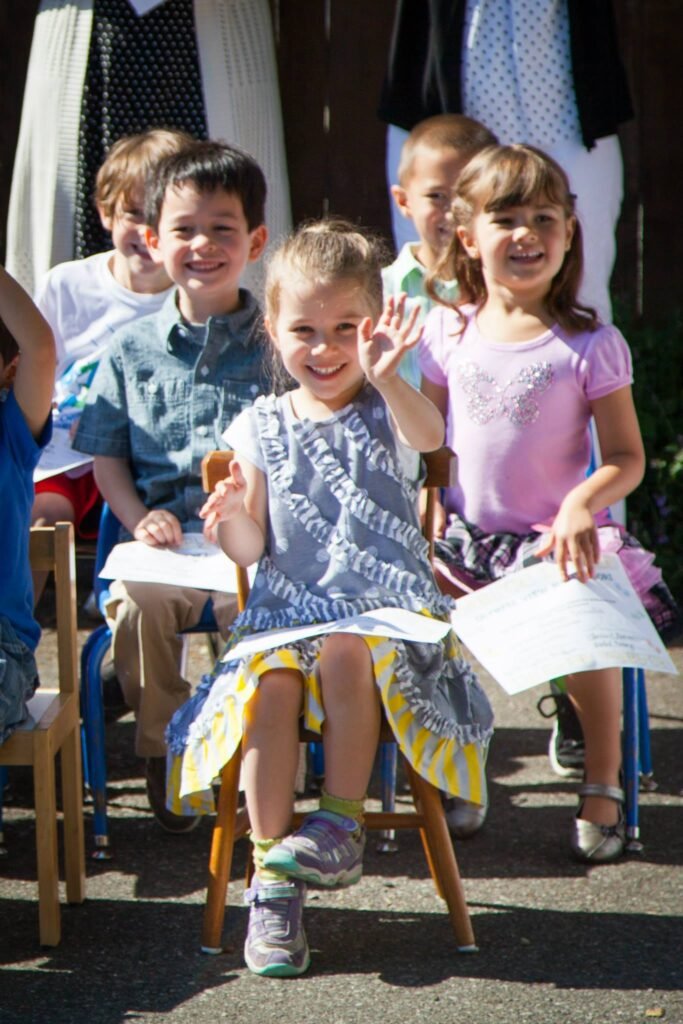 A group of happy children sitting outside on sunny day with papers.
