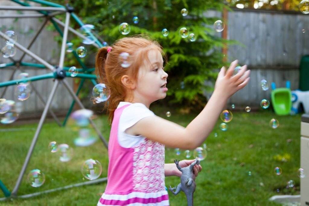 Achildreachestowardfloatingbubblesnearacousticgeodesicdomeinyard