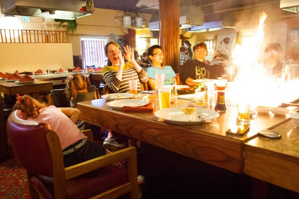 A group of people seated at a bustling table in a cozy café, enjoying drinks and light chatter. The atmosphere is lively and inviting.