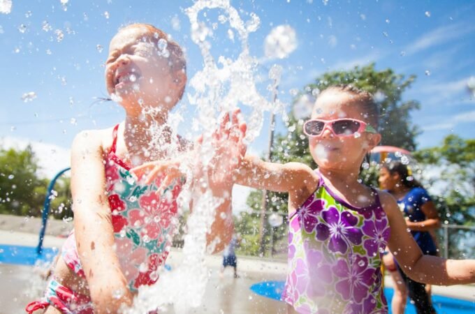 Children playing and splashing in a water park with bright blue skies and vibrant clothing.