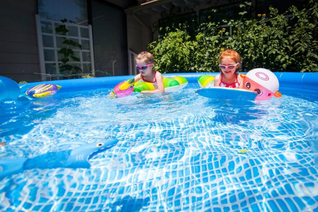 Children enjoy swimming in a backyard pool with colorful floaties.