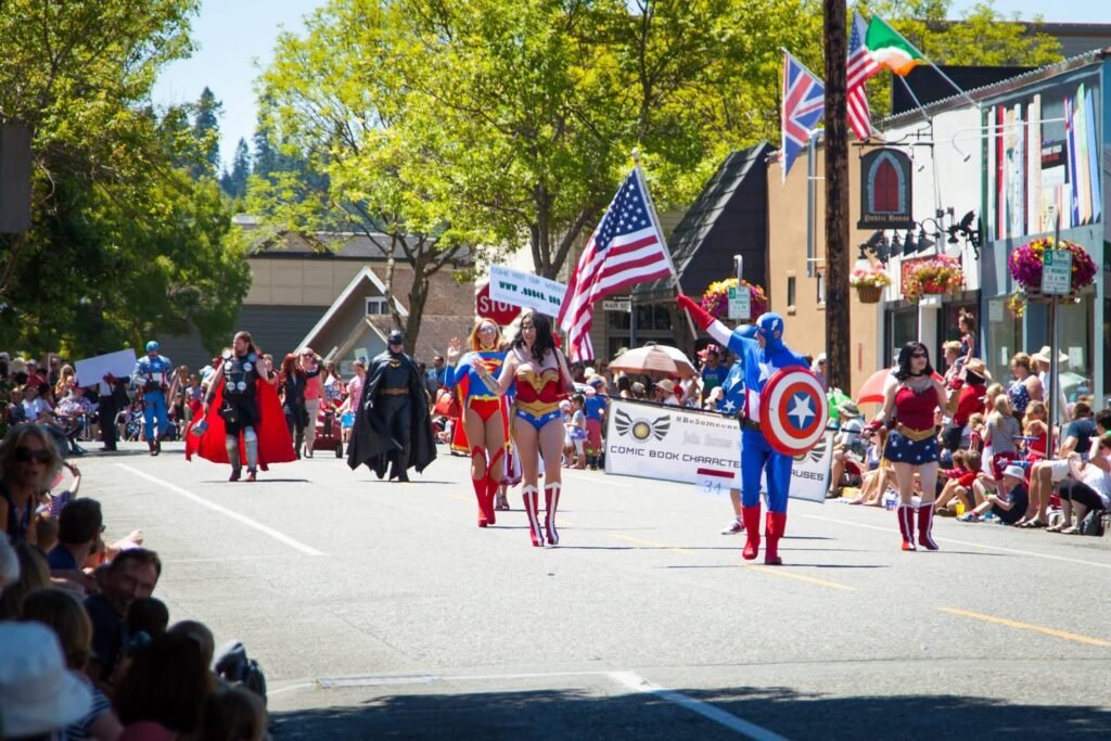 Colorful costumed marchers and spectators at a daytime street parade in a historic Pacific Northwest town.