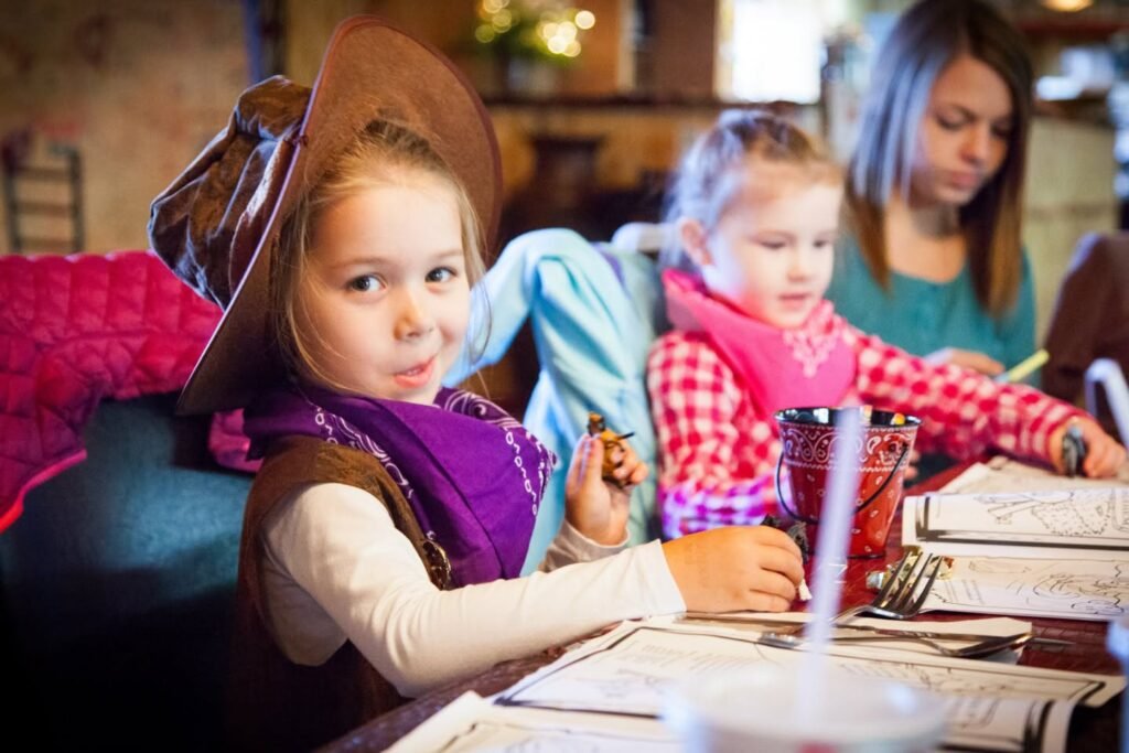 Two children at a restaurant table with an adult in the background.
