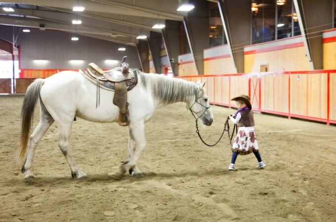 A young teenager practicing basic horse handling in an indoor arena.
