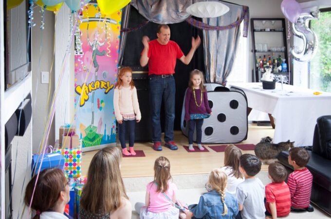 A magician performs a magic show for a group of children at a birthday party, featuring colorful decorations and props.