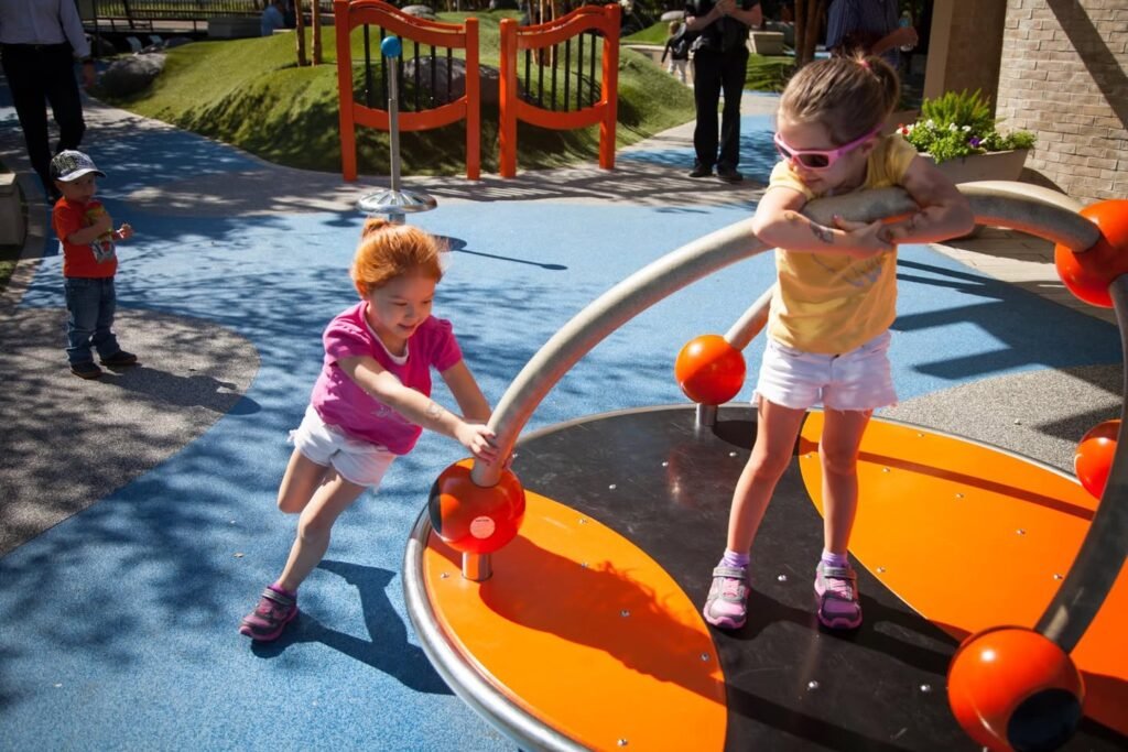 Children playing on a spinning playground ride on a sunny day.
