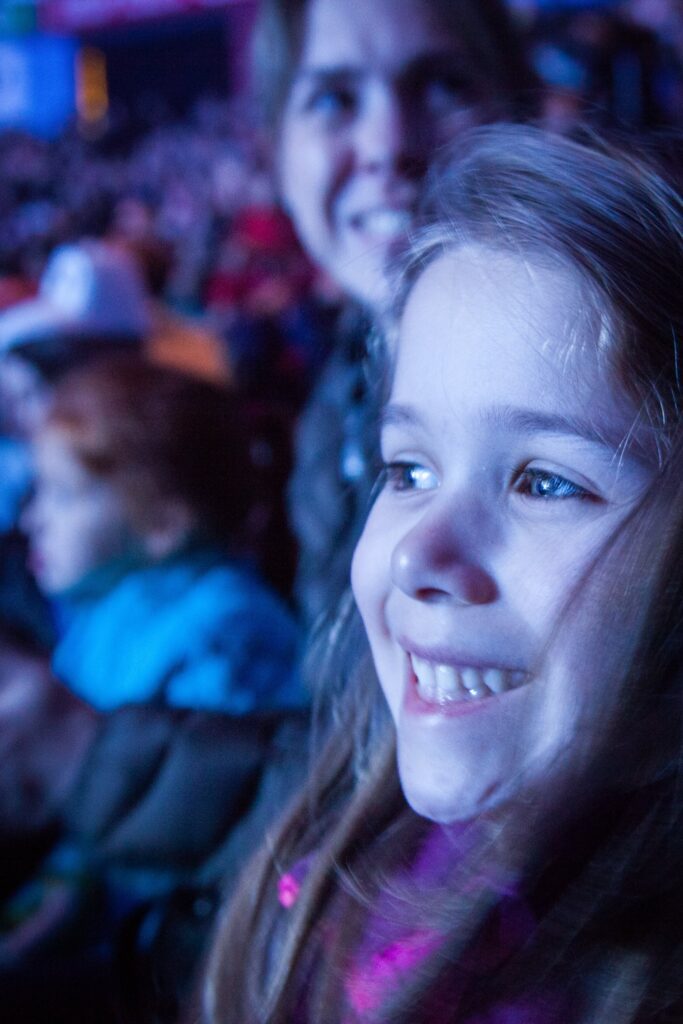 People are smiling under ambient light at an outdoor nighttime gathering.