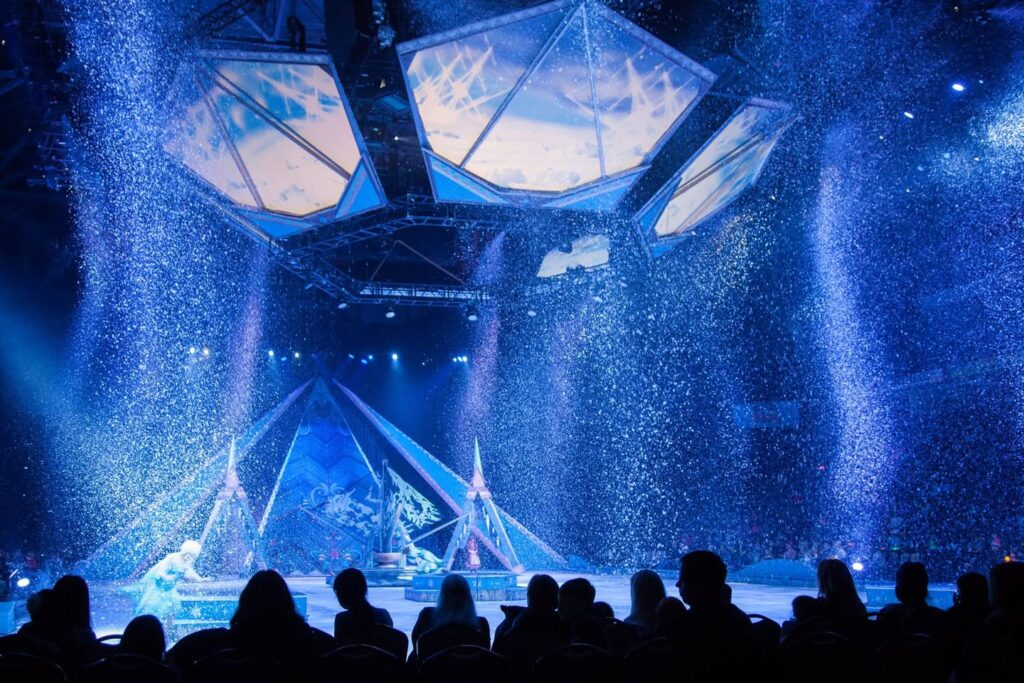 A mesmerizing nighttime water show with dramatic blue lighting and silhouetted audience.
