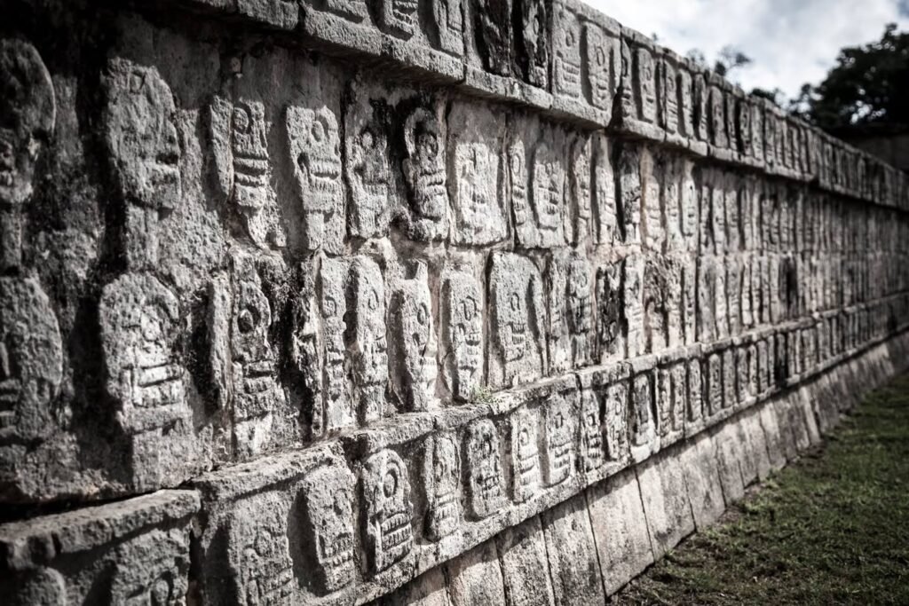 A series of ancient stone walls adorned with intricate Mayan carvings, showcasing detailed figures and glyphs.