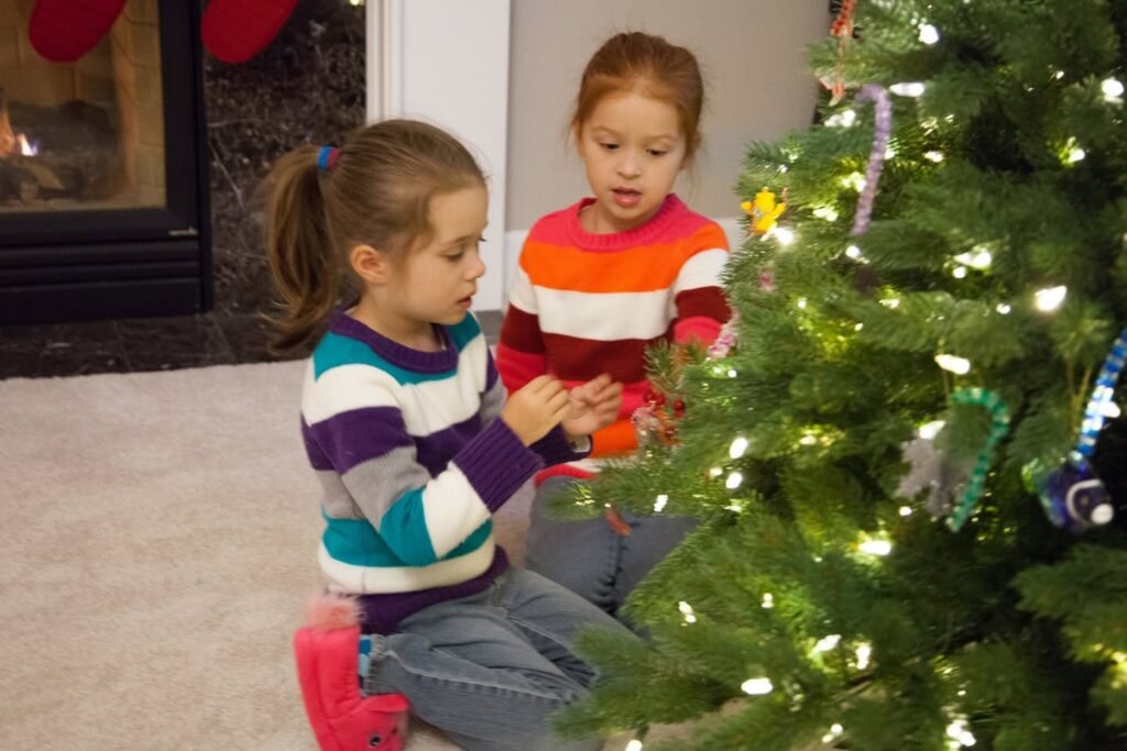 Children decorate a Christmas tree with colorful lights and ornaments in a warm home setting.