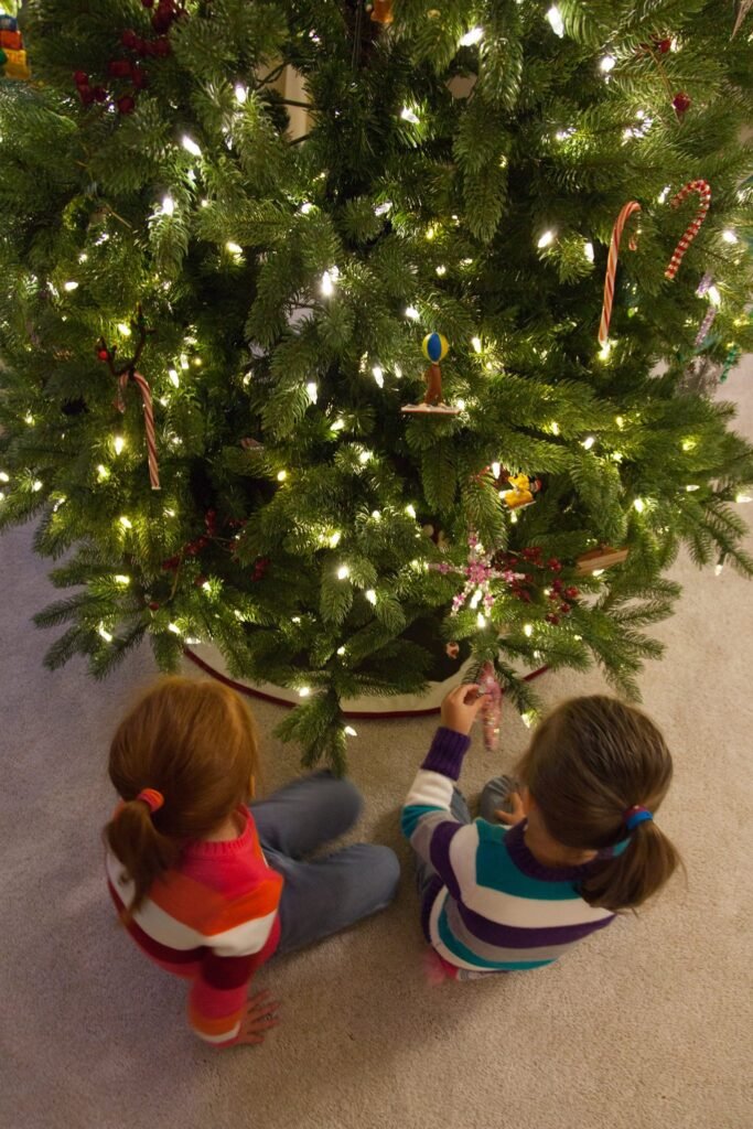 Children decorates a festive Christmas tree with candy canes, star ornament, and twinkling lights.