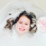 A smiling child peeks through a sea of bubbles in a warm bath. Fun and cozy moment captured at home.