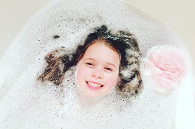 A smiling child peeks through a sea of bubbles in a warm bath. Fun and cozy moment captured at home.