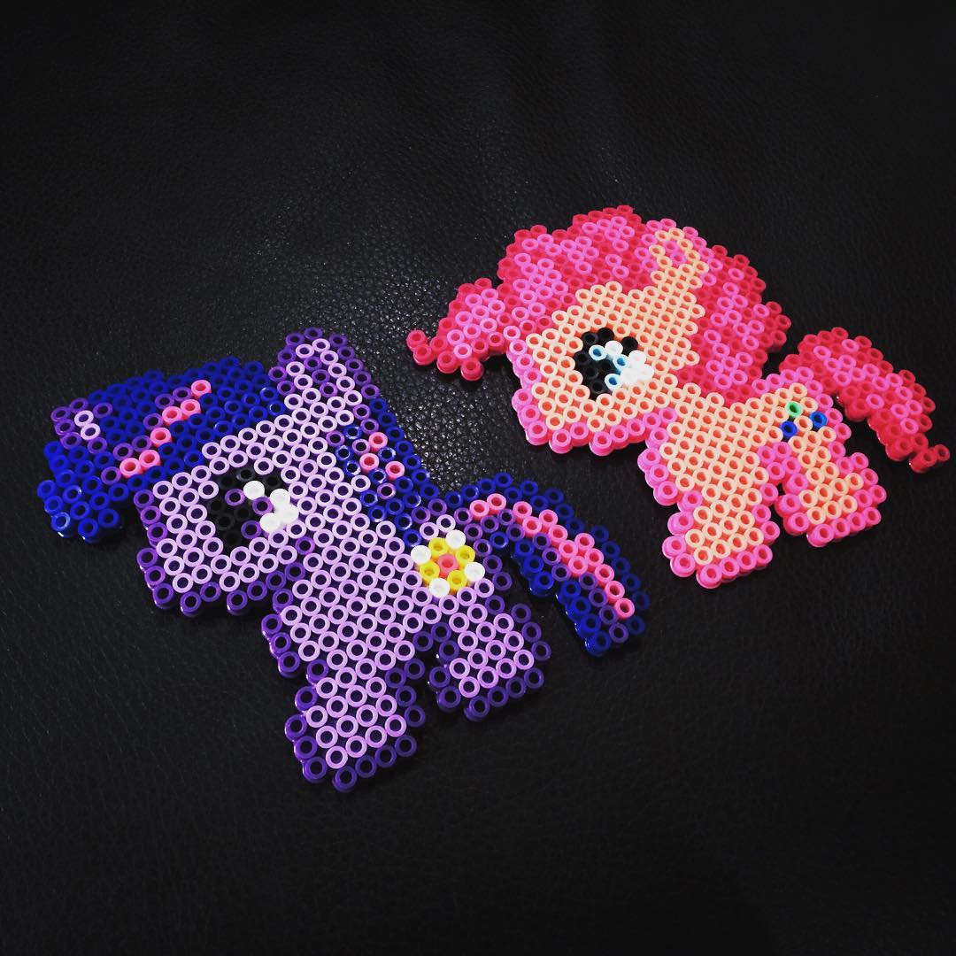 Handcrafted purple and pink pony figures made from Perler beads.