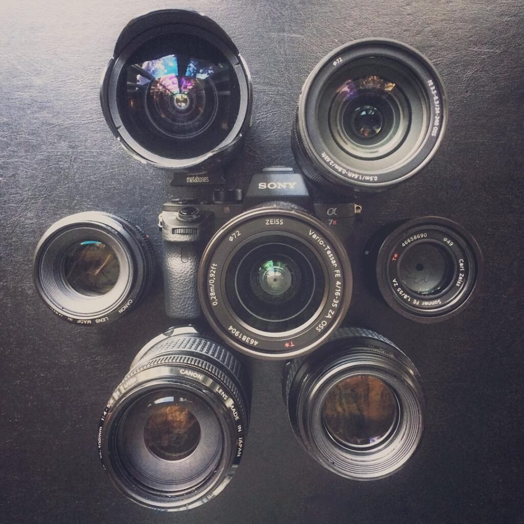 A SLS camera surrounded by six different lenses. Top-down view on dark surface.