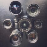 Camera Eulogy A SLS camera surrounded by six different lenses. Top-down view on dark surface.