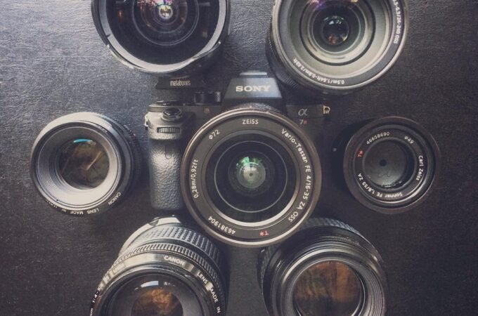 A SLS camera surrounded by six different lenses. Top-down view on dark surface.