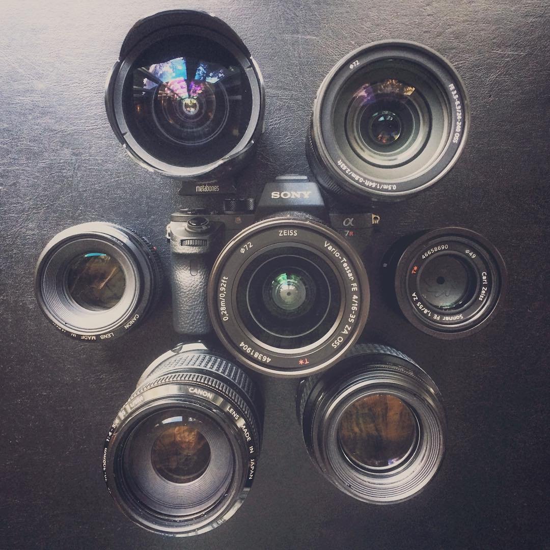 A SLS camera surrounded by six different lenses. Top-down view on dark surface.