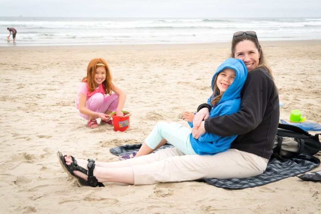 A group sharing a warm moment on a sandy beach with gentle waves in the background.