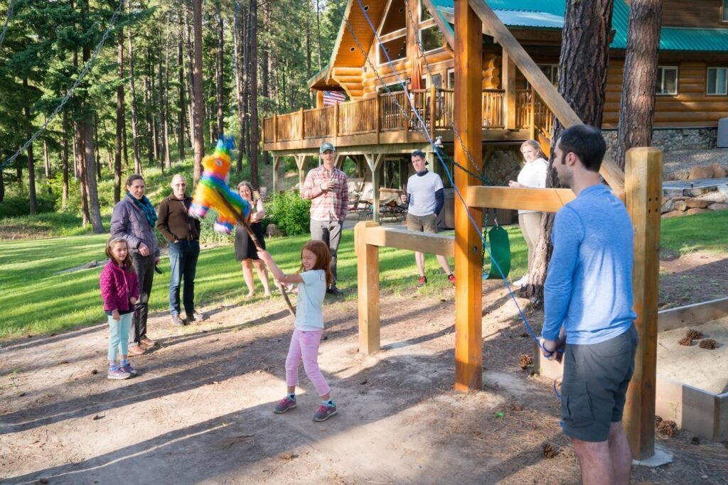 A child prepared to hit a colorful piñata at a Pacific Northwest cabin while others watch.