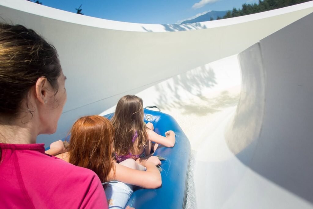 A group of people enjoying a white waterslide ride on a blue raft under a clear blue sky.
