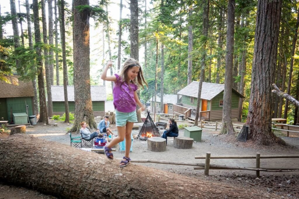 Balance beam at a forest campsite with cabins and campfires. Kids enjoying outdoor play in sunny Pines.