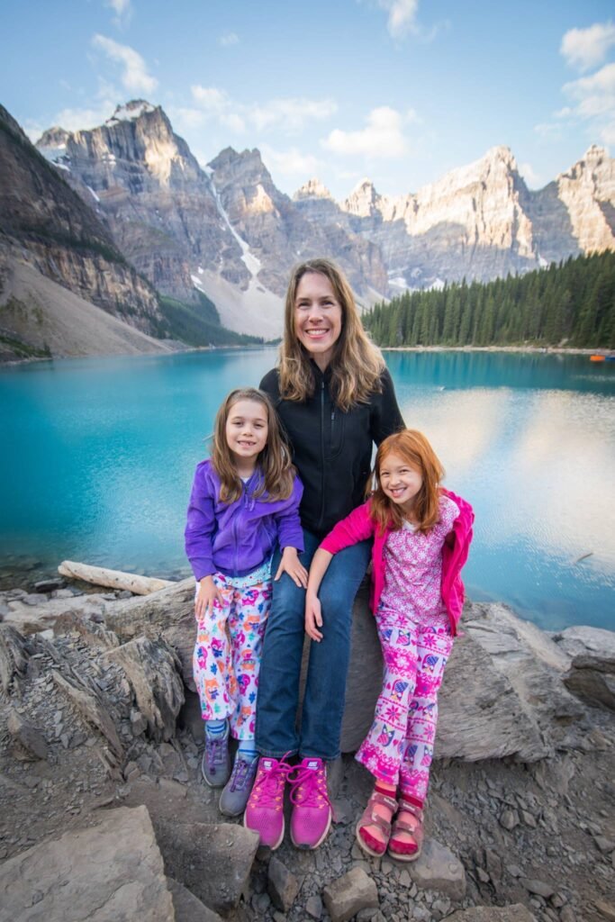 Family posing on rocks in front of a turquoise mountain lake.