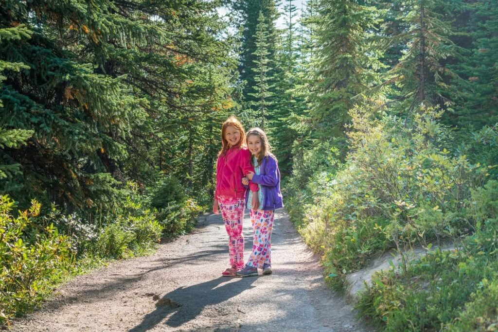 Two people walking on a forest trail surrounded by lush greenery. The image captures a peaceful outdoor scene in a serene nature setting.