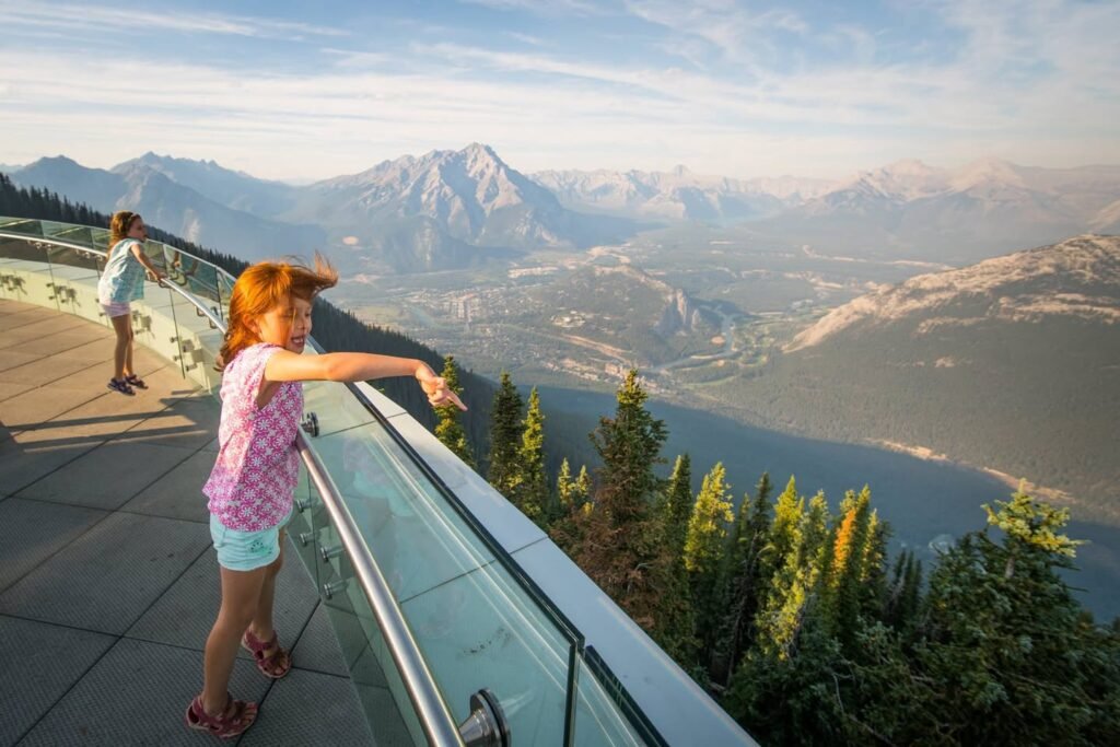 A scenic overlook offers a breathtaking perspective of misty mountains, a valley, a winding river, and a serene lake.
