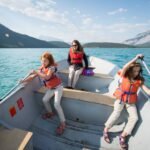A collage of photos showing people wearing life jackets rowing a boat on turquoise water with mountains in the background.