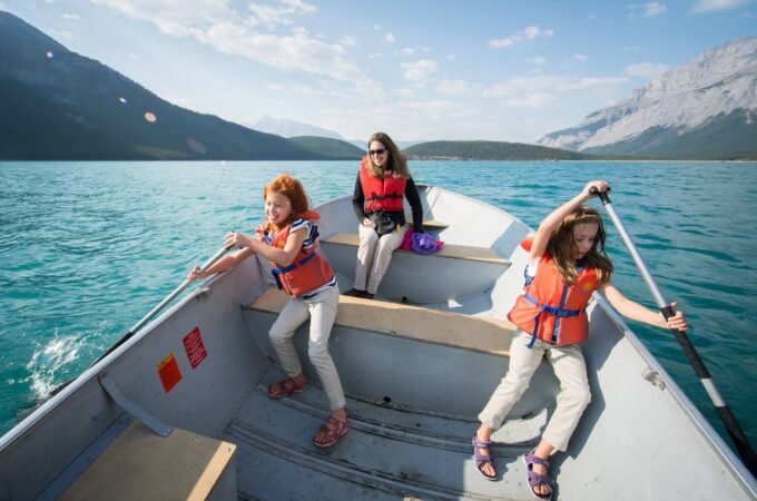 A collage of photos showing people wearing life jackets rowing a boat on turquoise water with mountains in the background.
