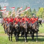 A mountie mounted on a horse in a red uniform.