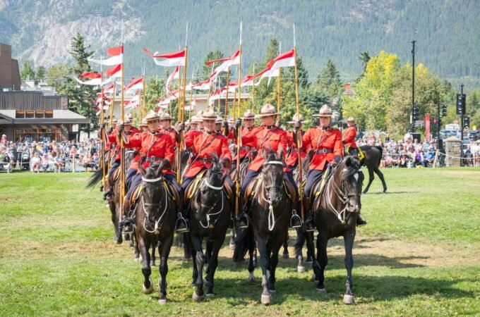 A mountie mounted on a horse in a red uniform.