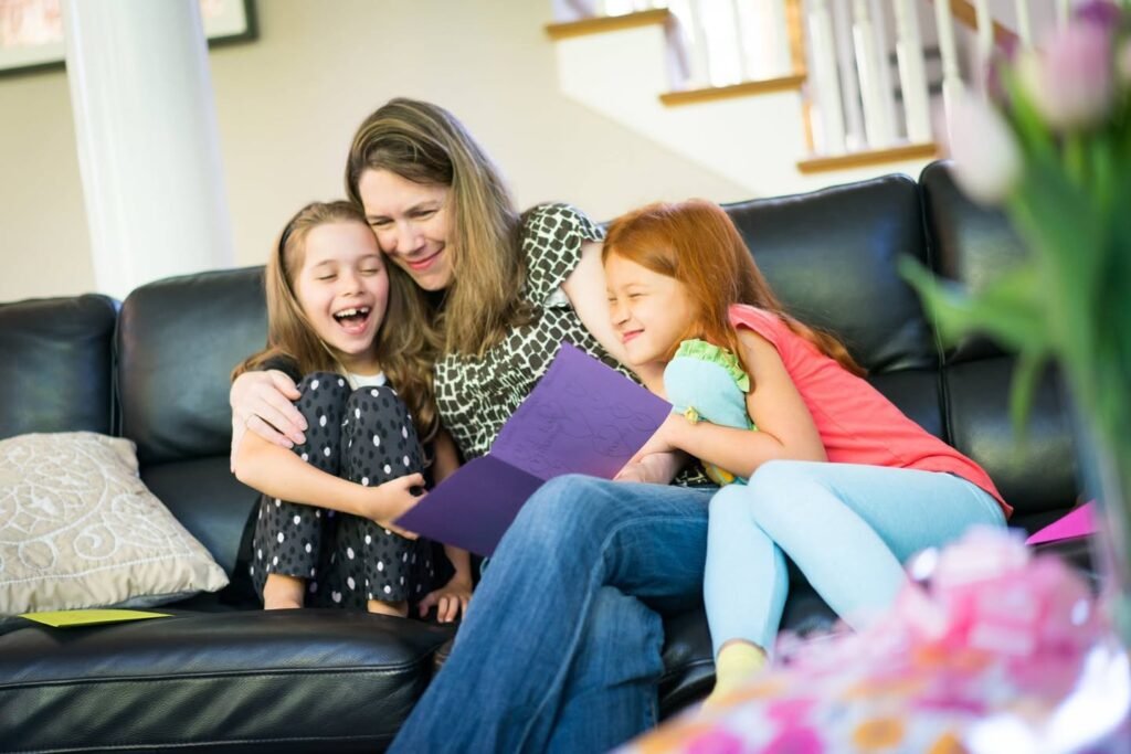 A family share a laugh with a purple card in a cozy living room.