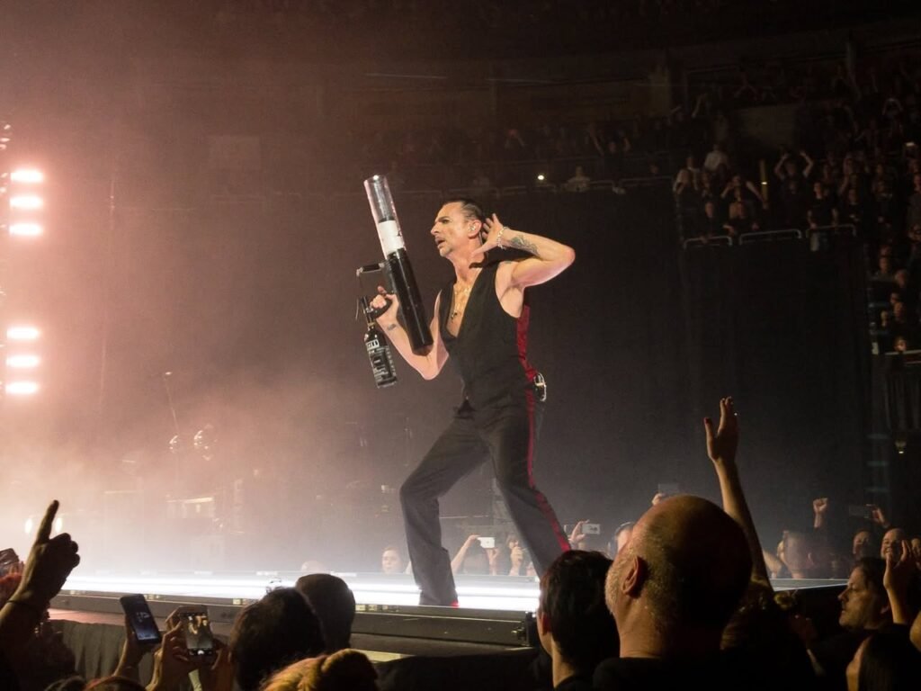 A performer on stage under bright lights with an engaged audience.