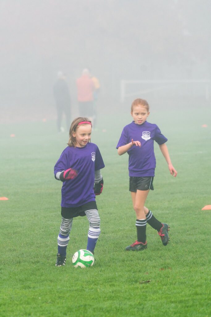 Young players in purple soccer uniforms on a foggy field.
