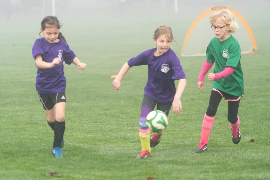Young soccer players in a match on a grassy field with foggy background; close-up action shots of the game.