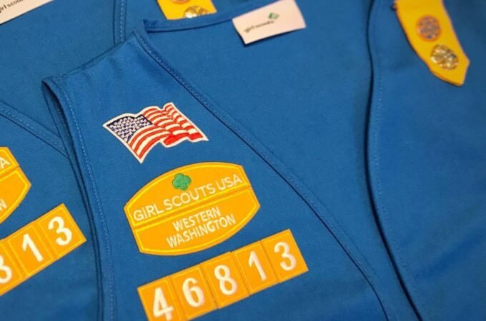 Blue Girl Scout vests featuring American flags and a Girl Scouts USA Western Washington patch. Troop number 46813 is displayed on a yellow patch.
