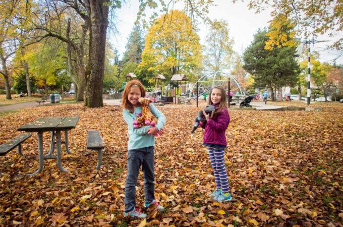 Children playing in a fallen leaf filled park in autumn.
