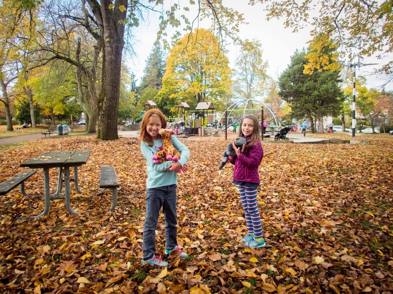 Children playing in a fallen leaf filled park in autumn.