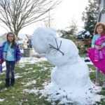 Family enjoying a winter day by building a snowman together.
