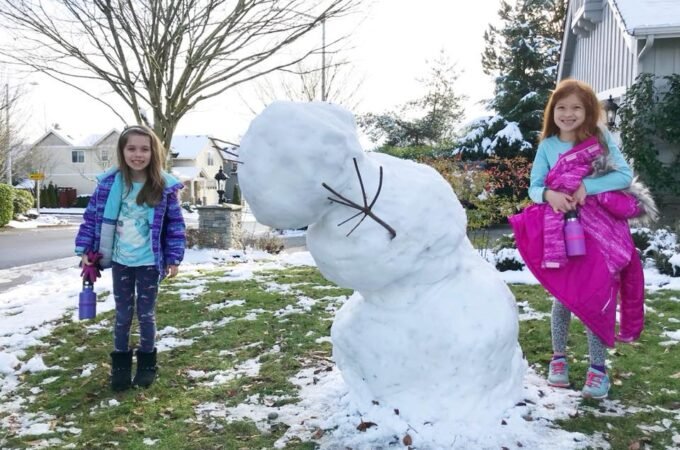 Family enjoying a winter day by building a snowman together.