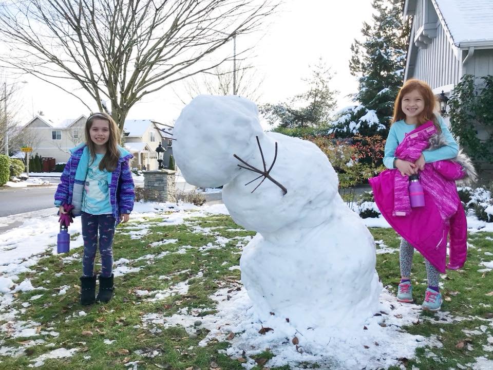 Family enjoying a winter day by building a snowman together.