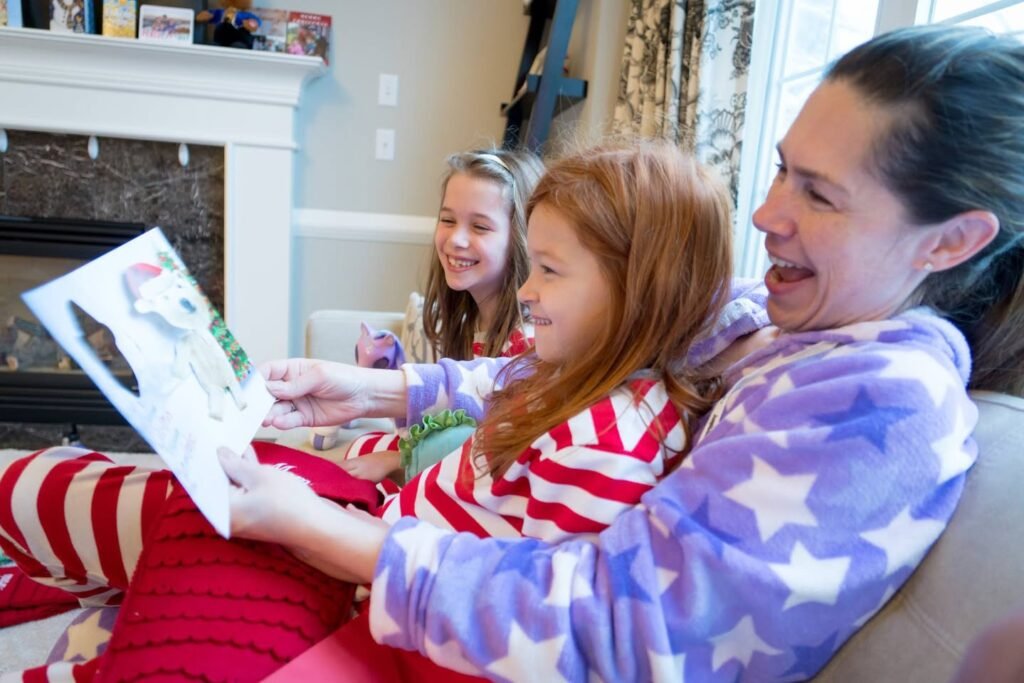 A woman and two children snuggling by a fireplace and sharing a book, wearing cozy pajamas.