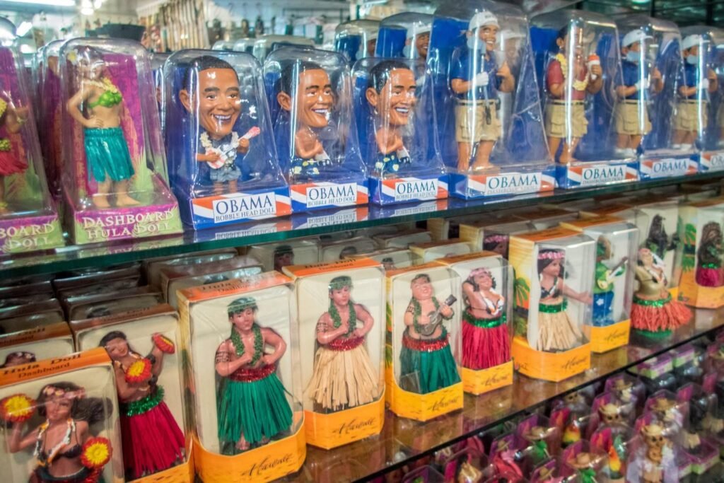 Shelves displaying novelty figurines of a political figure in various costume roles alongside cultural dance figures.