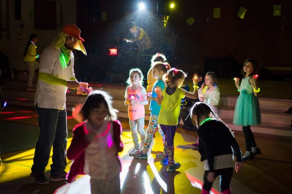 Children wearing glow sticks at night during an evening event. adults and youth enjoy glow-in-the-dark activities under lights.