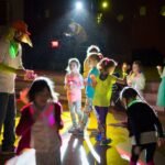 Children wearing glow sticks at night during an evening event. adults and youth enjoy glow-in-the-dark activities under lights.