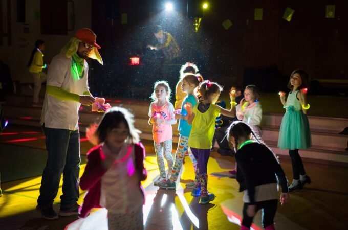 Children wearing glow sticks at night during an evening event. adults and youth enjoy glow-in-the-dark activities under lights.